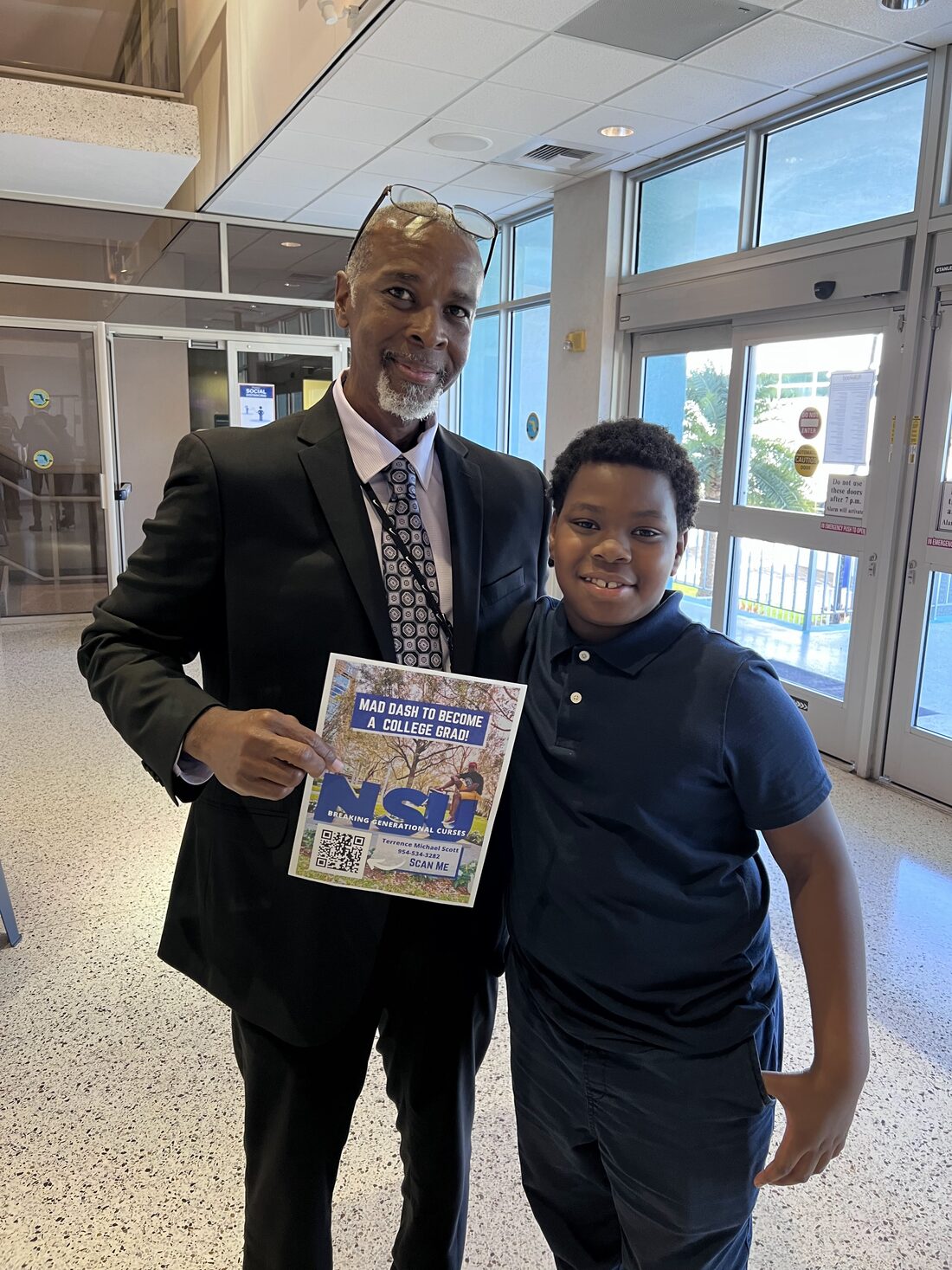 A supporter holding the Mad Dash to College Grad flyer with a young student